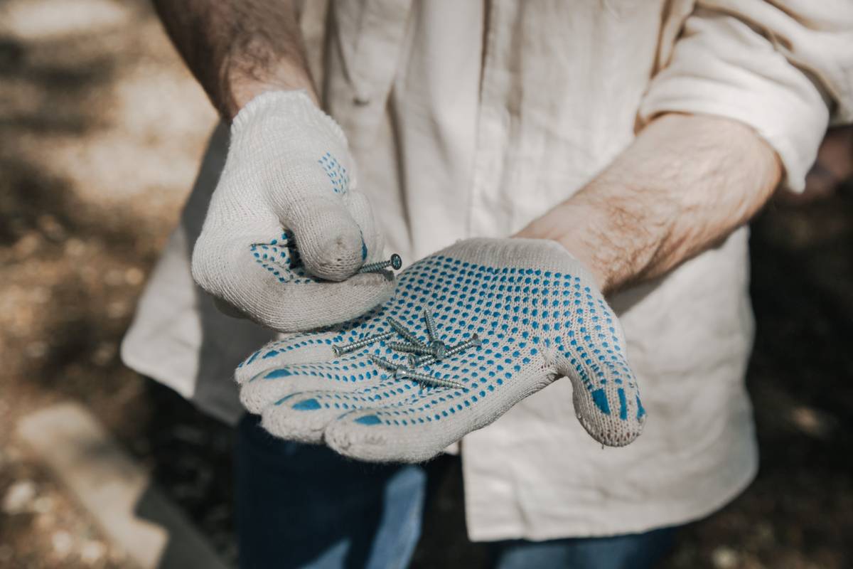 Gloved hands holding a handful of wood screws